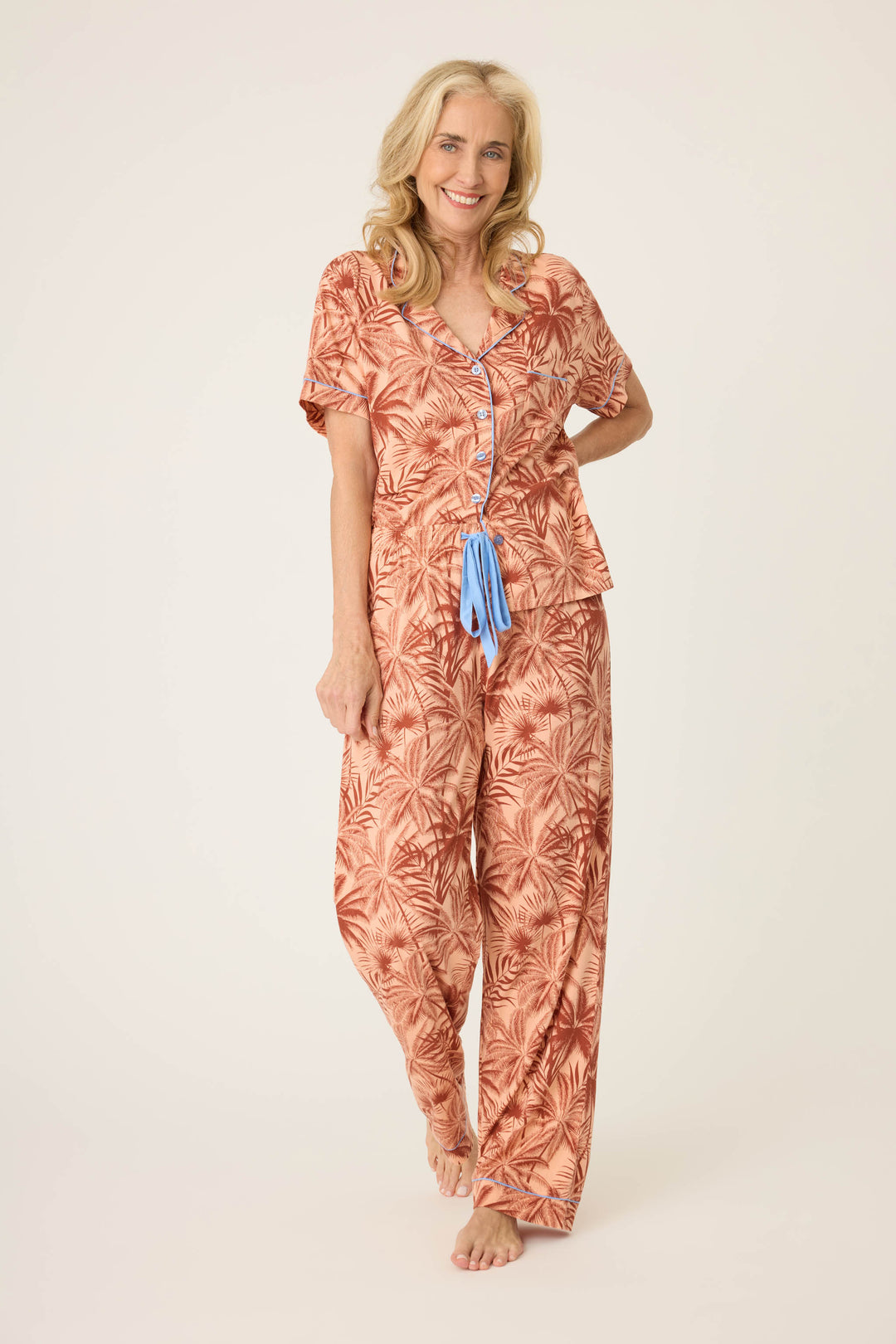 Women's breathable cotton-modal jersey short sleeve pajama set in amber-tan palm print with contrast blue piping. Button-front top & open leg tie-waist pant.