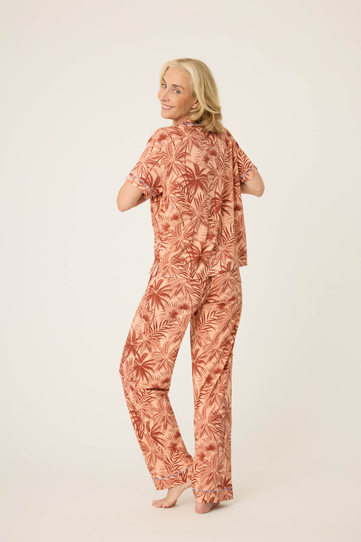 Women's breathable cotton-modal jersey short sleeve pajama set in amber-tan palm print with contrast blue piping. Button-front top & open leg tie-waist pant.