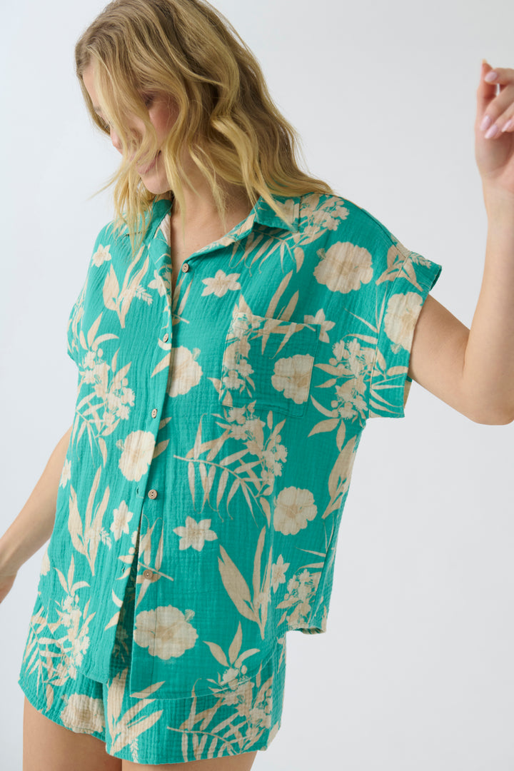 Women's short sleeve cotton woven gauze with green tropical print. Button-front with chest pocket.