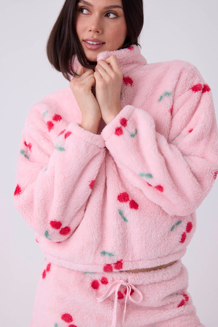 Women's pink fuzzy faux fur jacket with cherry pattern.