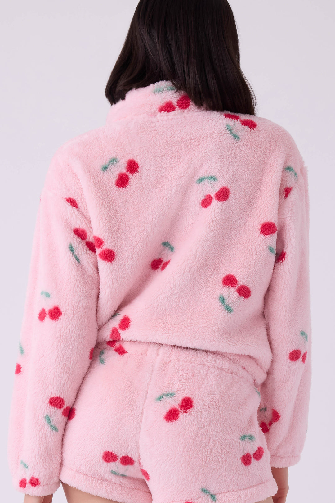 Women's pink fuzzy faux fur jacket with cherry pattern.