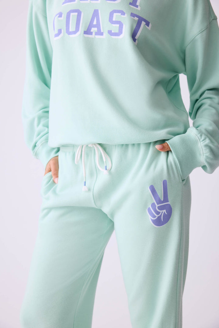 Women's vintage fleece jogger set in light green with EAST COAST graphic print.